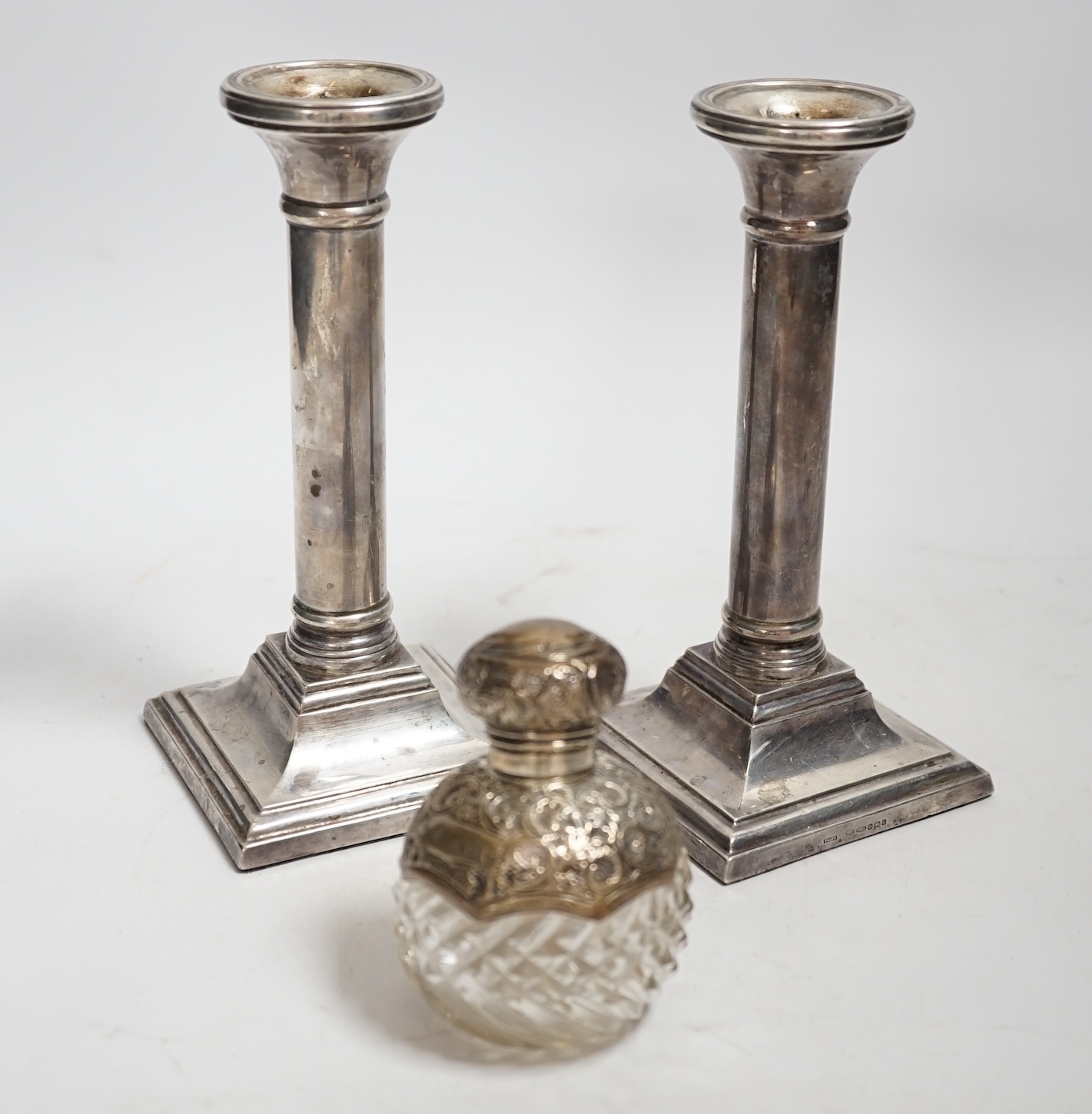 A pair of modern silver mounted candlesticks, 17cm, weighted, together with an Edwardian silver mounted cut glass scent bottle.